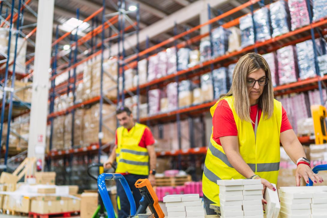 Warehouse workers picking and packing inventory in a modern fulfillment center with shelving and shipping operations visible