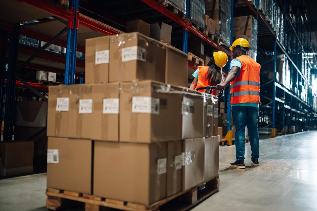 Warehouse workers moving palletized boxes in fulfillment center, representing 3PL operations and order shipping process